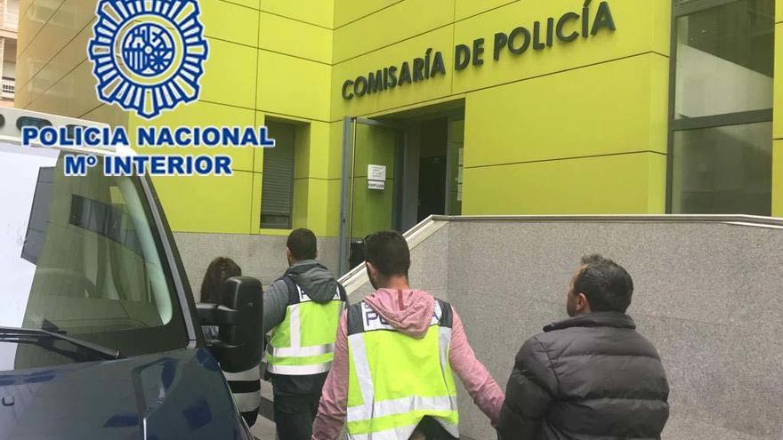 Dos agentes llevan a comisaría a uno de los detenidos.