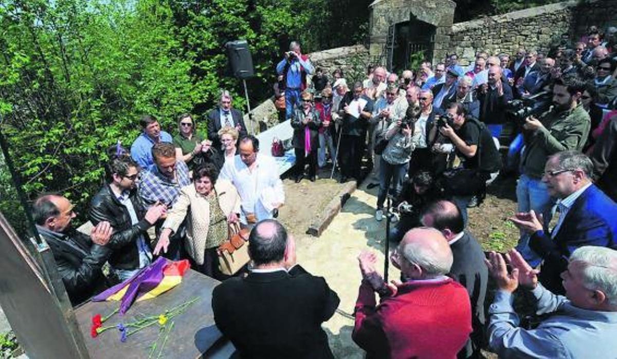 Cari Quintana, hermana de uno de los guerrilleros, coloca unas flores y la bandera de la República en el monolito.