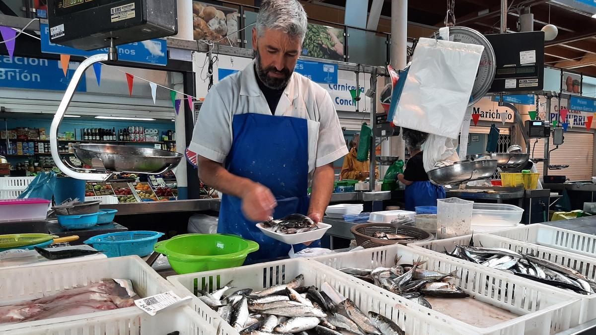 Un pescadero de la plaza de Bueu prepara una bandeja con pescado para un cliente.