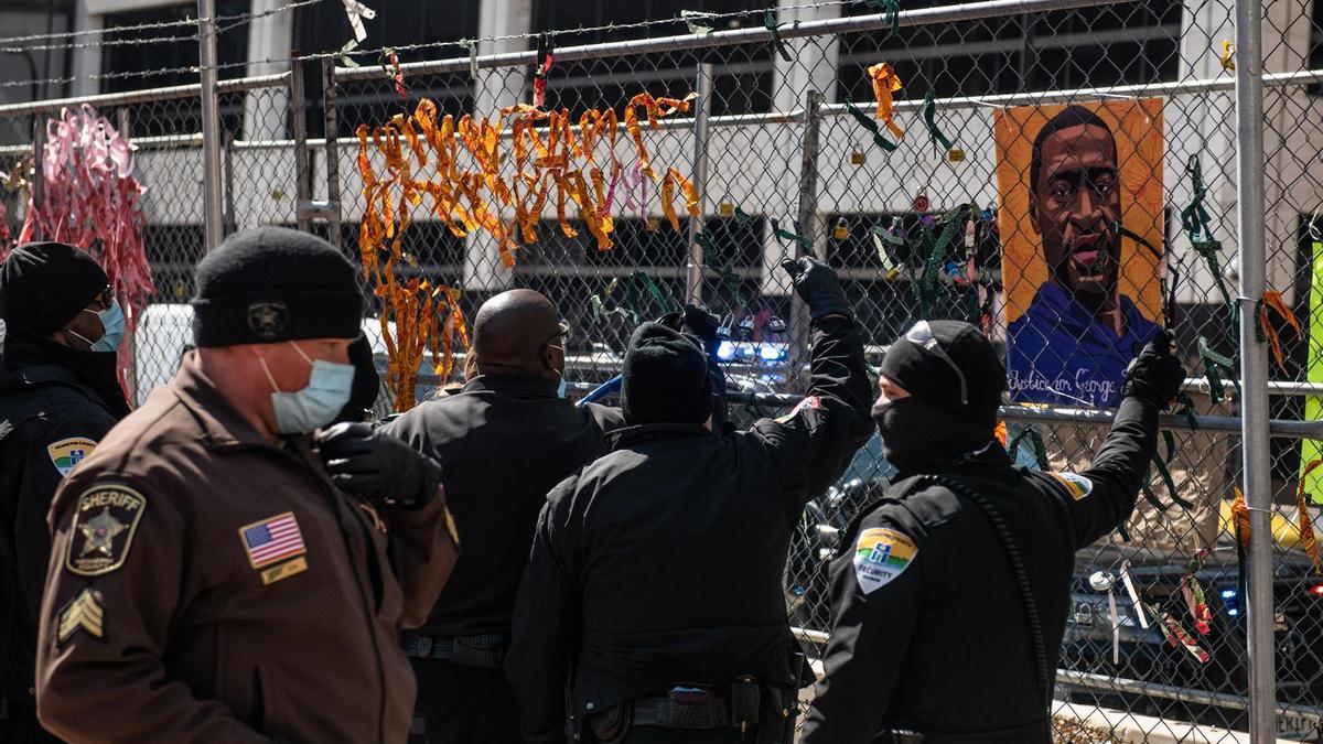 Policías retiran imágenes de George Floyd en las afueras del juzgado del condado de Hennepin, donde se celebra el juicio por su muerte.