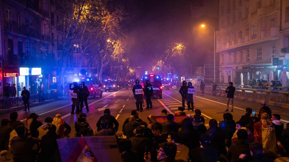 Demonstranten vor Polizisten der Nationalpolizei während einer Demonstration in der Ferraz Straße. Im Ringen um die Regierungsbildung in Spanien haben die Sozialisten (PSOE) des geschäftsführenden Ministerpräsidenten Sánchez ein umstrittenes Abkommen auch mit der zweiten der beiden Separatisten-Parteien aus Katalonien erzielt. Die Amnestie soll unter anderem jenen Unabhängigkeitsbefürwortern zugutekommen, die 2017 an einem gescheiterten Abspaltungsversuch der Region im Nordosten Spaniens teilgenommen haben. Proteste richteten sich gegen die Amnestie.