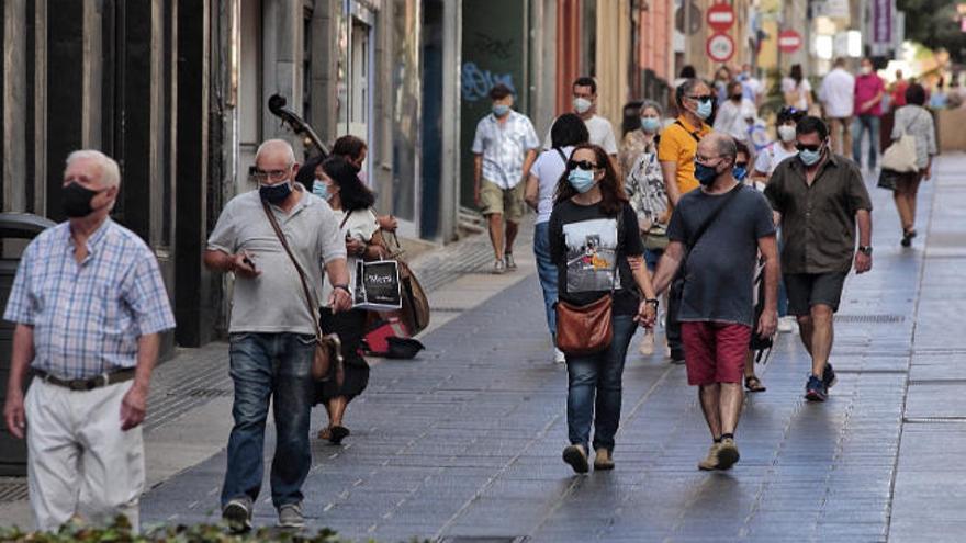 Varias personas con mascarilla transitan por la calle Del Castillo.