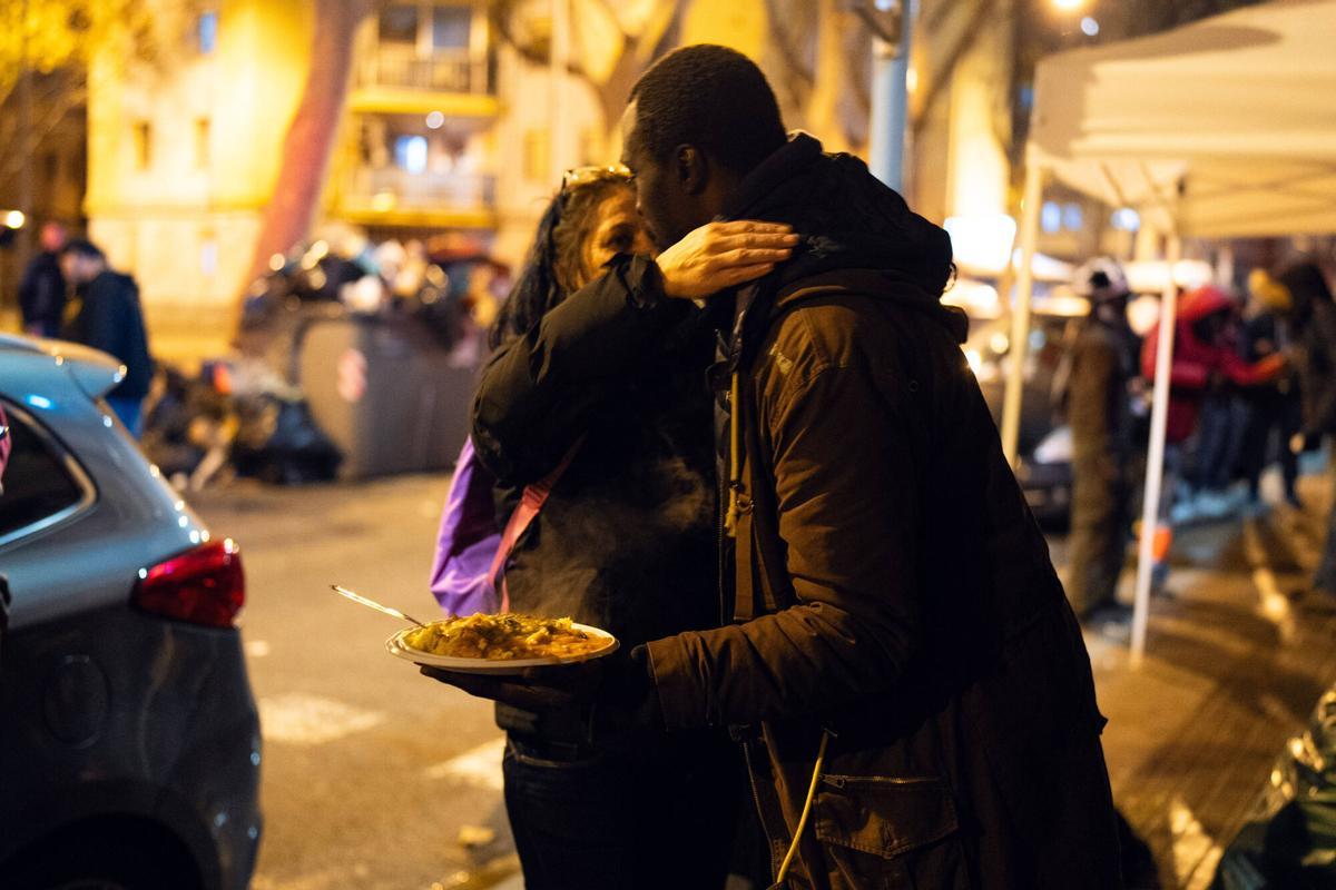 Voluntarios de distintas entidades privadas reparten comida para la cena de Nochebuena bajo la autopista C-31, donde aún duermen decenas de personas desalojadas del antiguo instituto B9