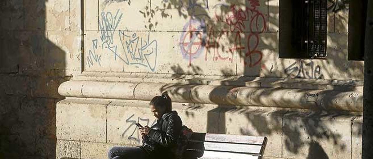 Una joven mirando su móvil en la conocida como ´plaza del tubo´ de Palma.