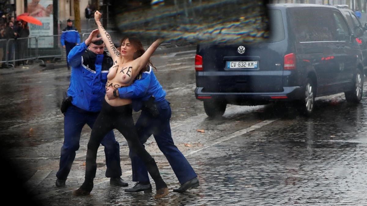 Un policía detiene a una ctivista de Femen mientras salta detrás del conboy de Donald Trump