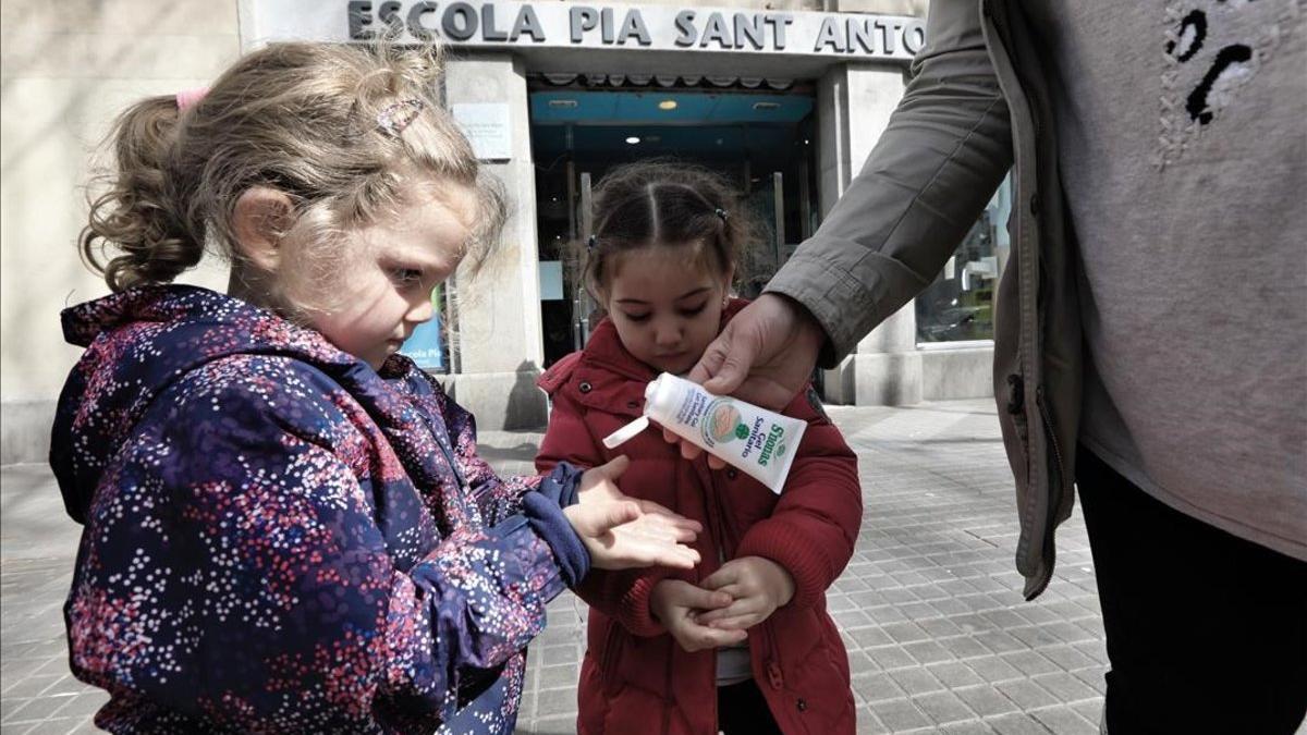 Dos niñas se aplican gel desinfectante al salir de la escuela, en Barcelona