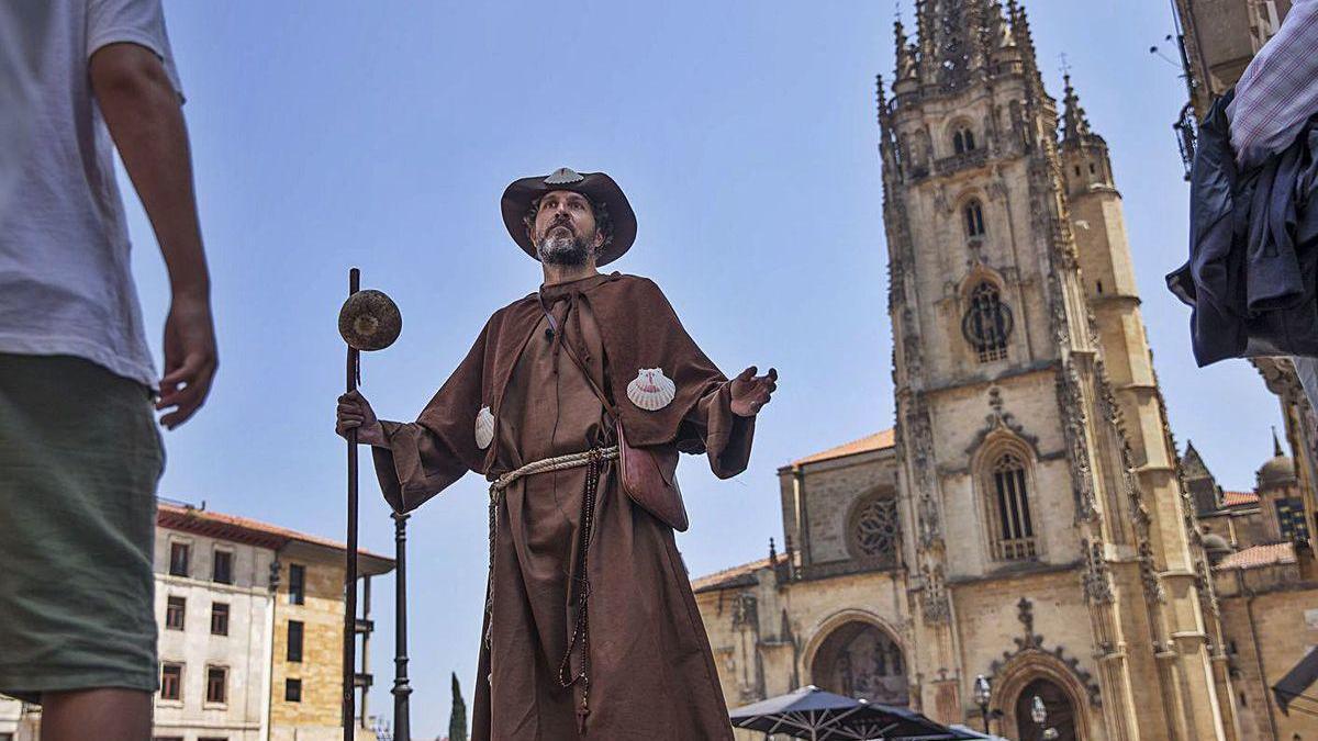 Un guía turístico ataviado como un peregrino jacobeo, con la Catedral al fondo.