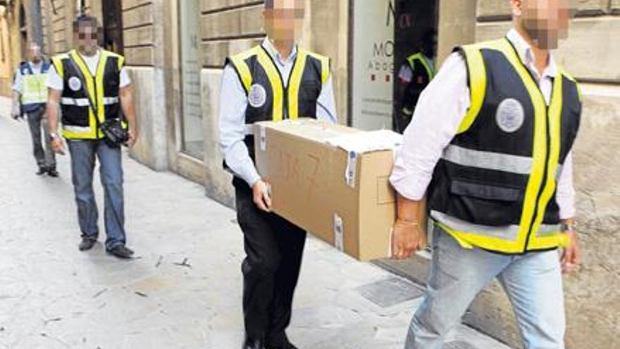 Policías sacando documentación del bufete Montis, en plena calle Sant Jaume.
