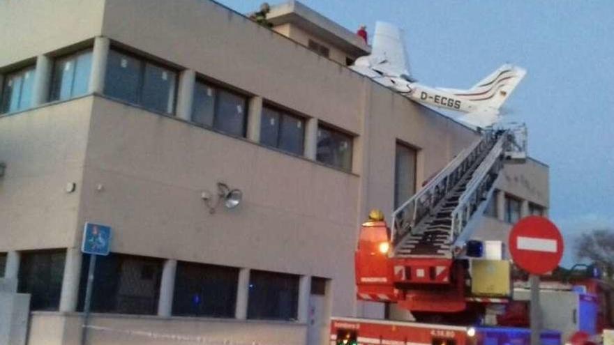 Los bomberos intentan acceder al tejado de la gasolinera donde se estrelló la avioneta.