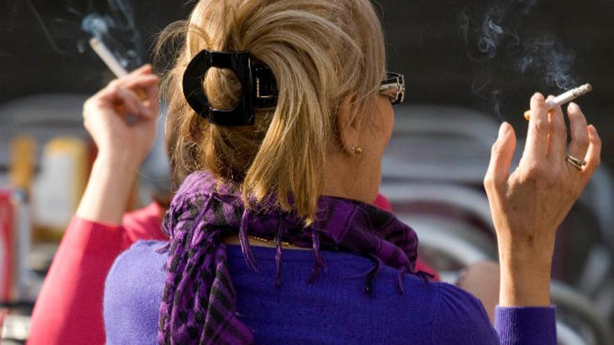 Una mujer fumando un cigarrillo en una terraza.