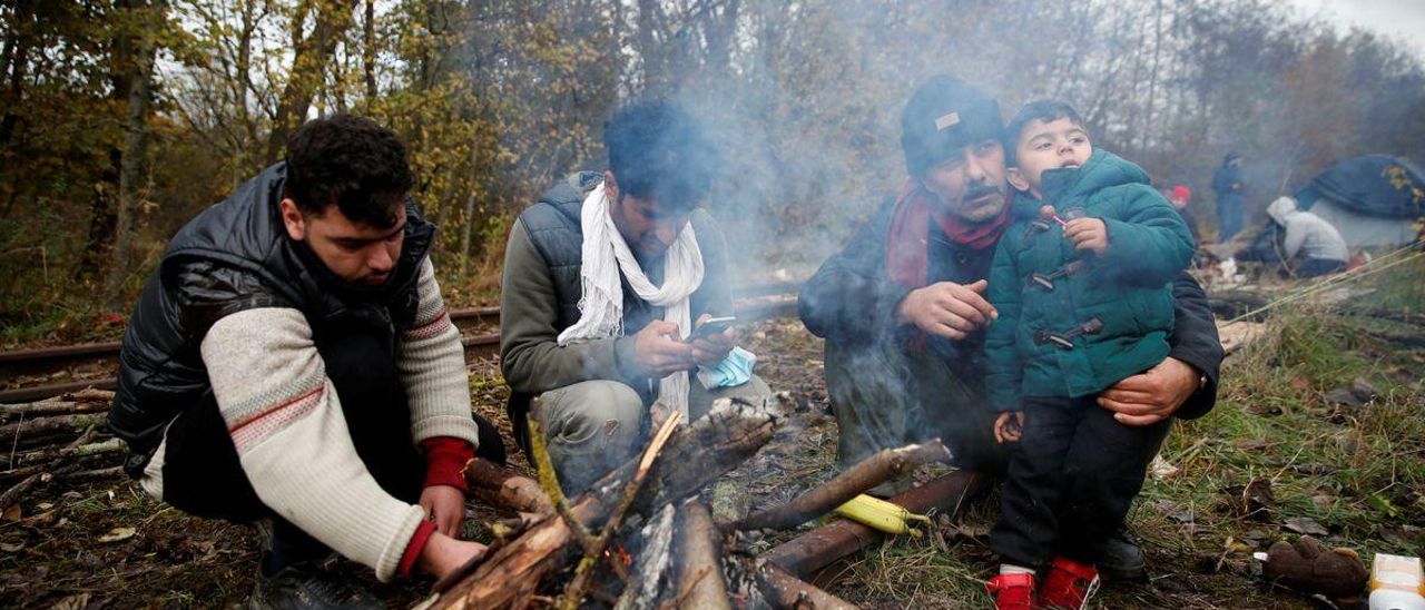 Un grupo de migrantes trata de calentarse frente a una hoguera en un campamento improvisado en las inmediaciones de Calais.