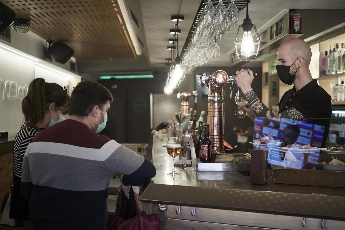 Archivo - Un camarero sirve una cerveza en el interior de un bar