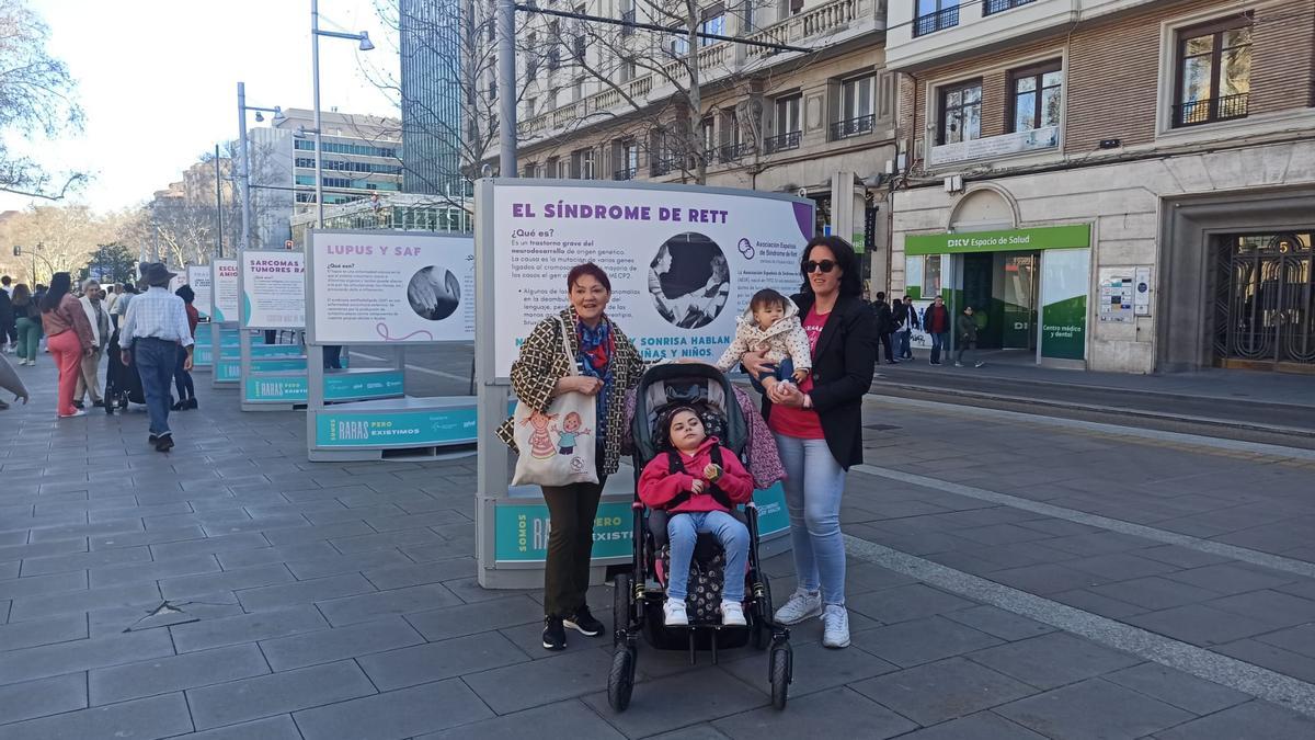 Fina Roselló, Sara y Rebeca, con su sobrina en brazos, posan con el cartel del síndrome de Rett.