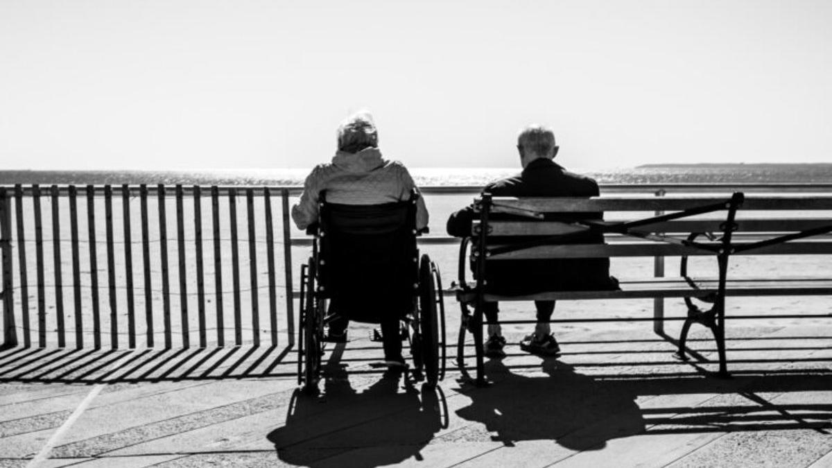 Dos ancianos descansan frente a un mirador.