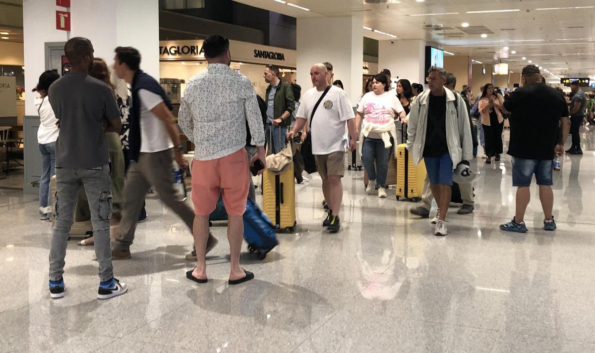 De espaldas, dos taxistas pirata habituales en la zona de llegadas del aeropuerto de Ibiza, en una imagen de archivo.