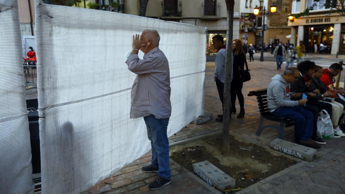 Gente mirando un espectáculo del Pilar a través de la malla.