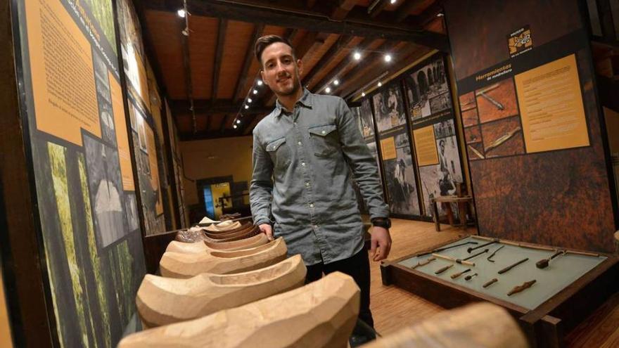 El guía del Museo de la Madera, ubicado en Veneros, ante varias madreñas de la exposición.