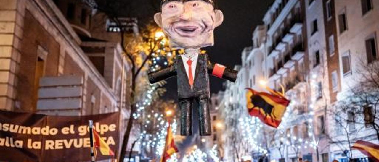 El muñeco que representaba a Pedro Sánchez es izado entre los manifestantes en la calle Ferraz el 31 de diciembre.