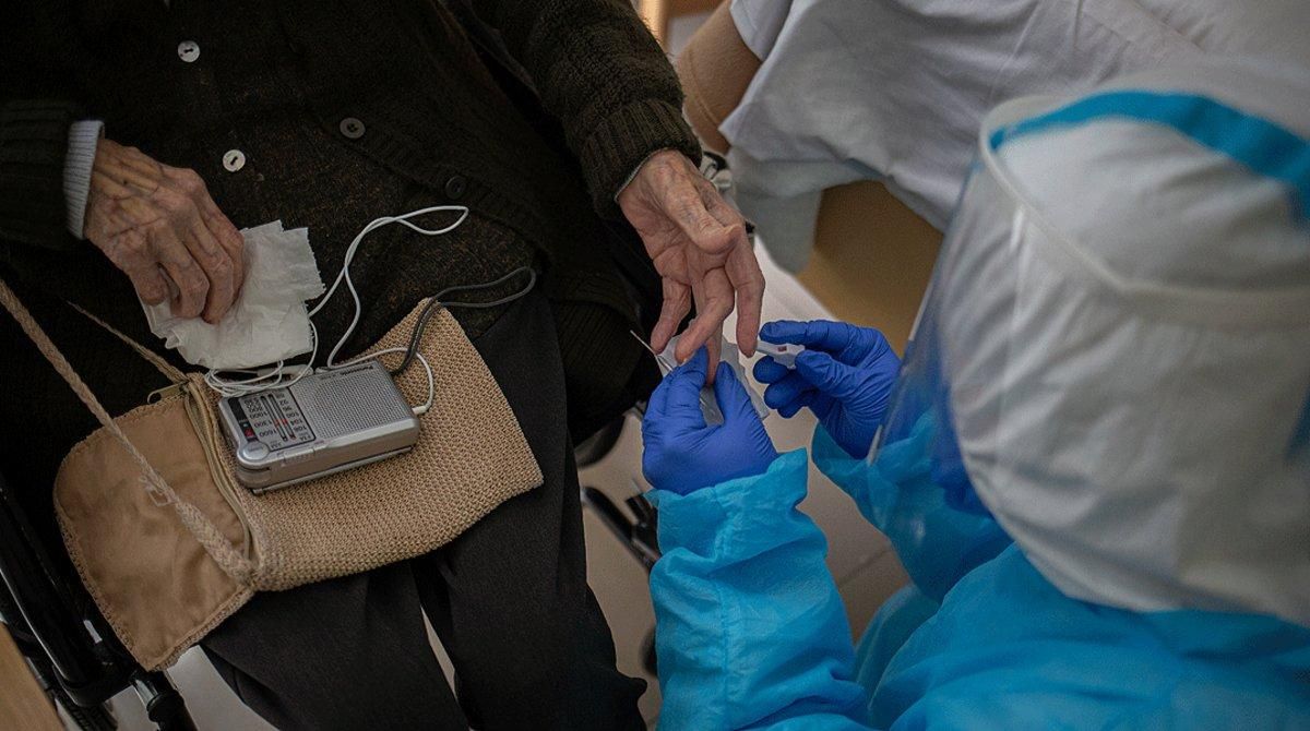 Un voluntario de la oenegé Proactiva Open Arms realiza un test rápido de covid-19 a un anciano de la Residencia Geriátrica Redós de Sant Pere de Ribes, el 30 de abril.