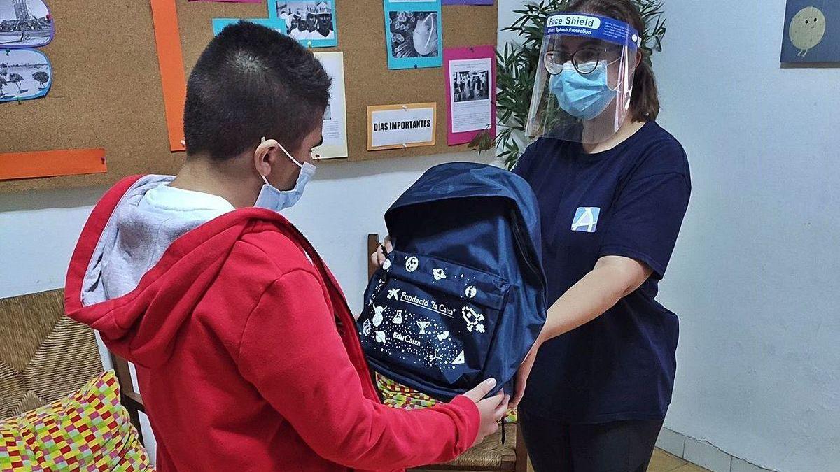 Un niño recibre uno de los kits de la Fundación &quot;la Caixa&quot; y CaixaBank.