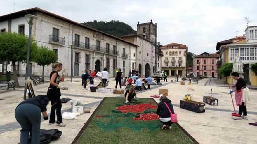 Voluntarios colocando las alfombras de la plaza de la Colegiata.