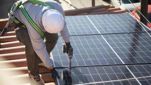 Un operario instala una planta solar en un tejado