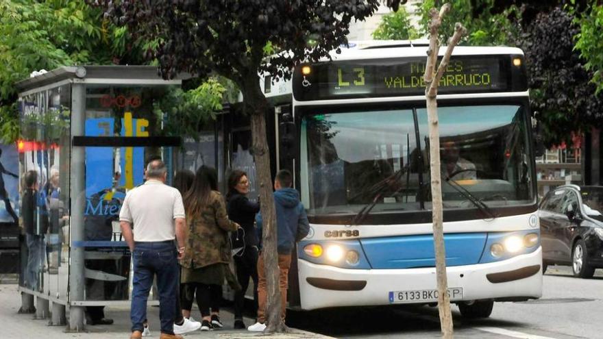 Usuarios de la empresa municipal acceden a un autobús en la parada de la calle Manuel Llaneza.