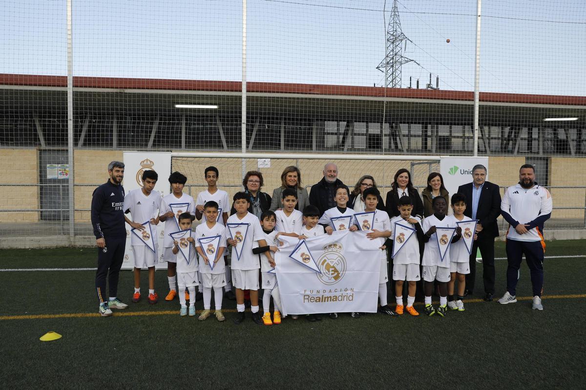 Los niños del primer turno de la escuela sociodeportiva de la Fundación Real Madrid en Oviedo posan con sus banderines, junto a entrenadores y varios representantes de asociaciones que hacen posible esta iniciativa.
