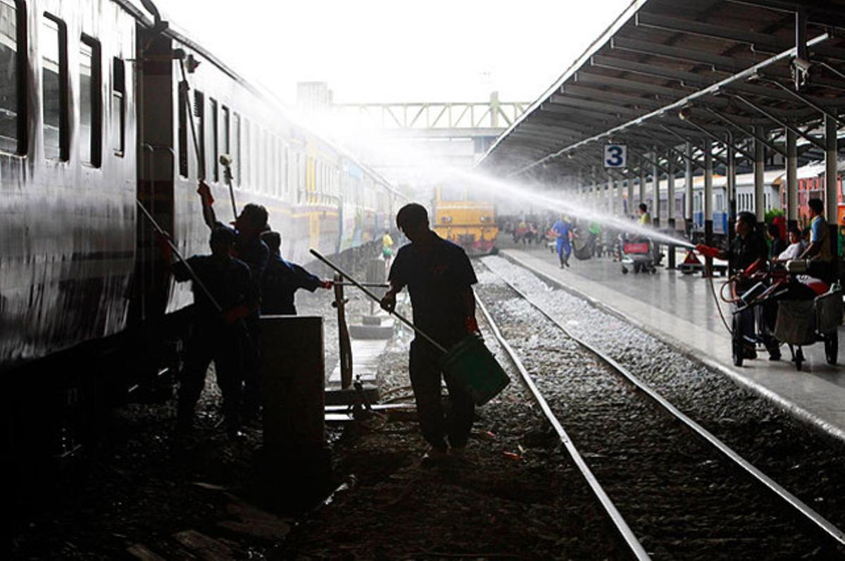 Dos treballadors netegen com a mesura preventiva contra la malaltia ’mà-peu-boca’ (MPB), en una estació de tren de Bangkok, després d’un brot recent.