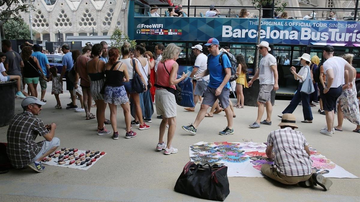 Manteros y turistas en los alrededores de la Sagrada Famíla.