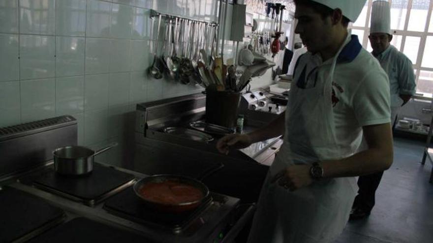 El touroperador José María Torelles, sartén en mano, preparando un plato en la escuela agroalimentaria.