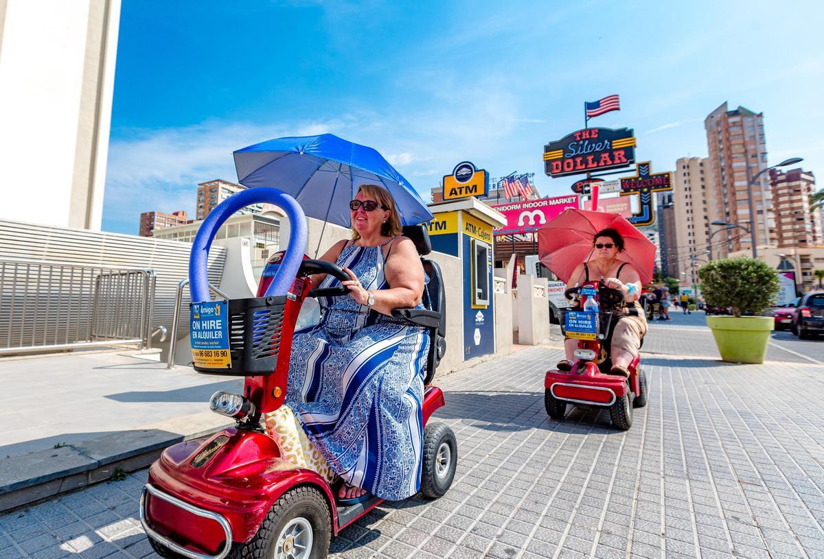 Turistas británicas con "scooters" eléctricos por Benidorm.