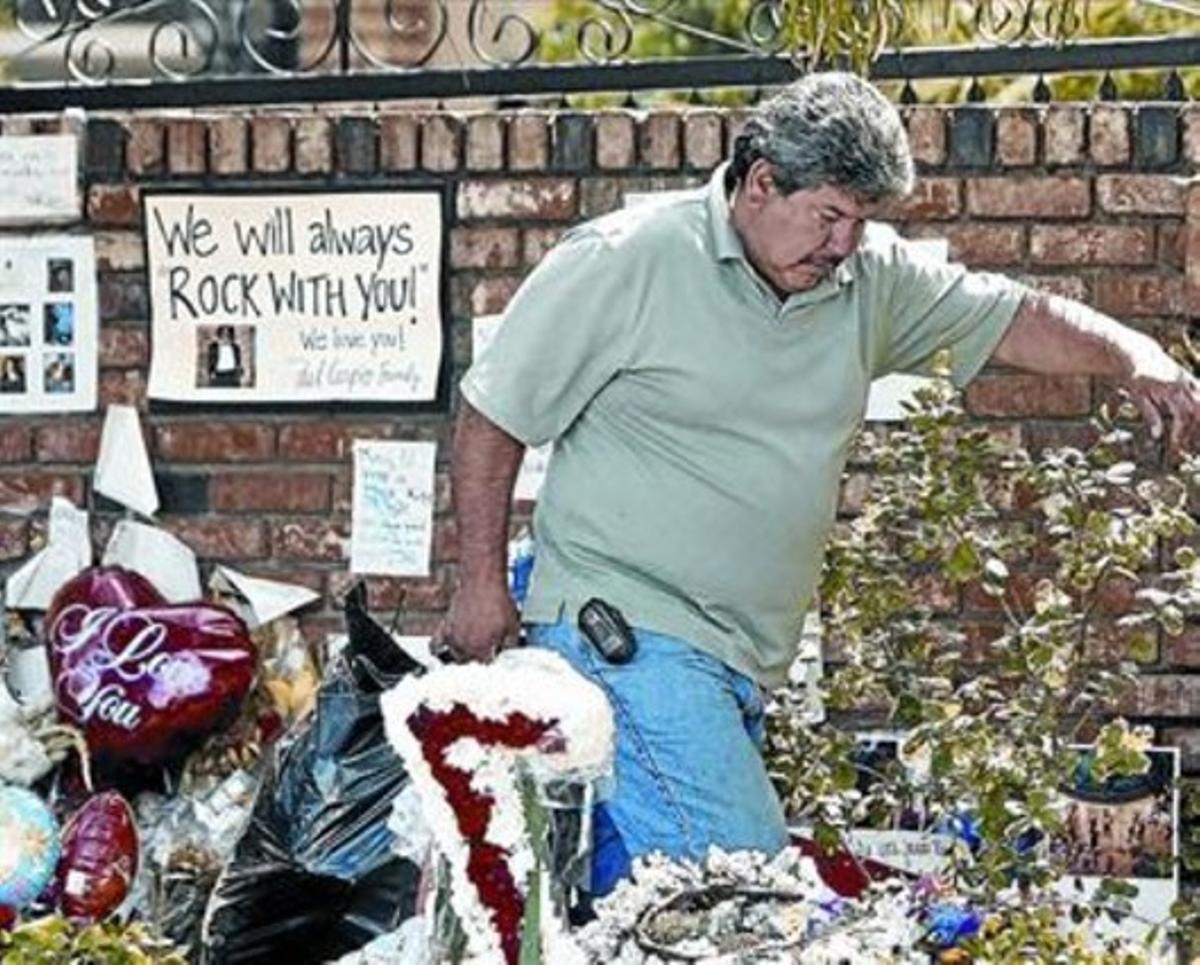 Un treballador recull les escombraries en l’improvisat monument a Jackson fora de la casa familiar.
