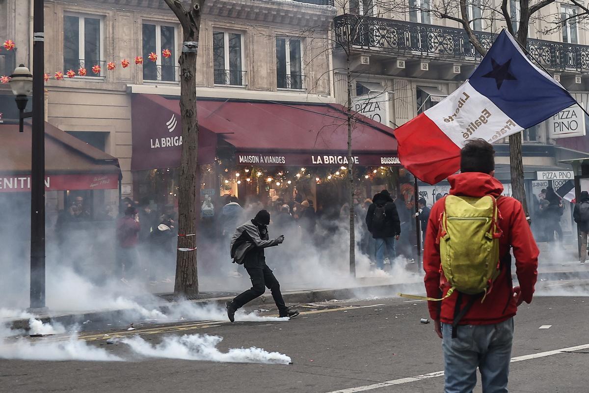 Paris (France), 23/03/2023.- A Protester kicks a tear gas bomb during clashes with anti-riot police, during a protest against government pension reform in Paris, France, 23 March 2023. Protests continue in France after the French prime minister announced on 16 March 2023 the use of Article 49 paragraph 3 (49.3) of the French Constitution to have the text on the controversial pension reform law be definitively adopted without a vote in the National Assembly (lower house of parliament). The bill would raise the retirement age in France from 62 to 64 by 2030. (Protestas, Francia) EFE/EPA/MOHAMMED BADRA