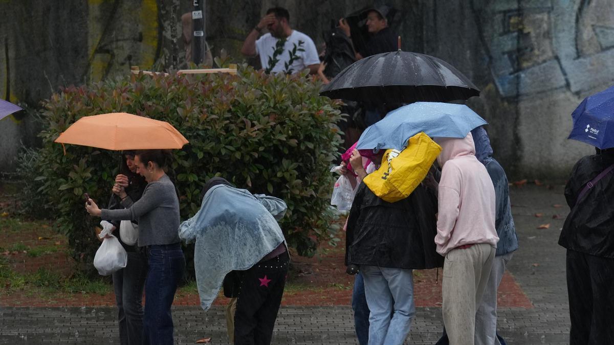 Diferents persones es protegeixen de la pluja sota paraigües