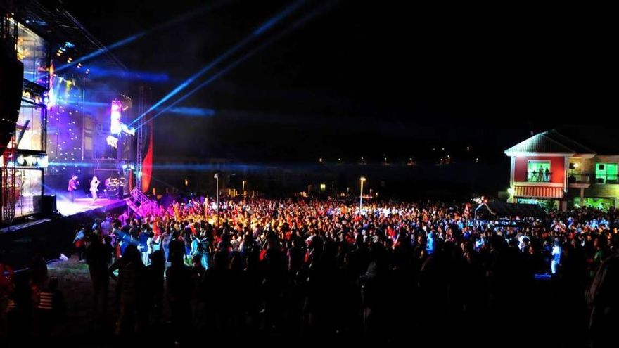 Cientos de personas escuchan a una orquesta situada sobre un gran escenario móvil en una fiesta de Carril.