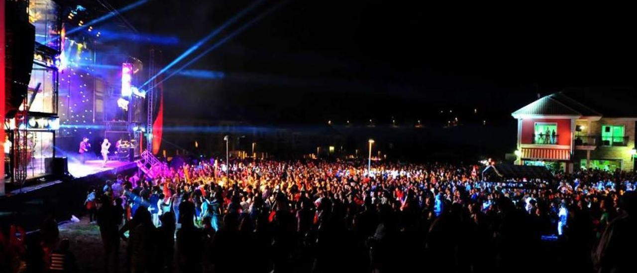 Cientos de personas escuchan a una orquesta situada sobre un gran escenario móvil en una fiesta de Carril.