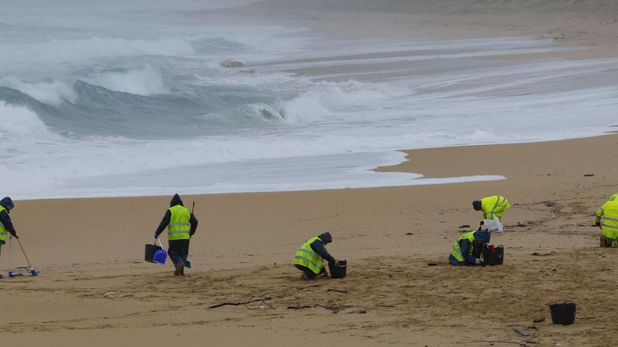 Operaris d’empreses contractades per la Xunta retiren els pèl·lets o boletes per fabricar plàstic, ahir a la platja d’O Vilar, a la Corunya. | LAVANDEIRA JR / EFE