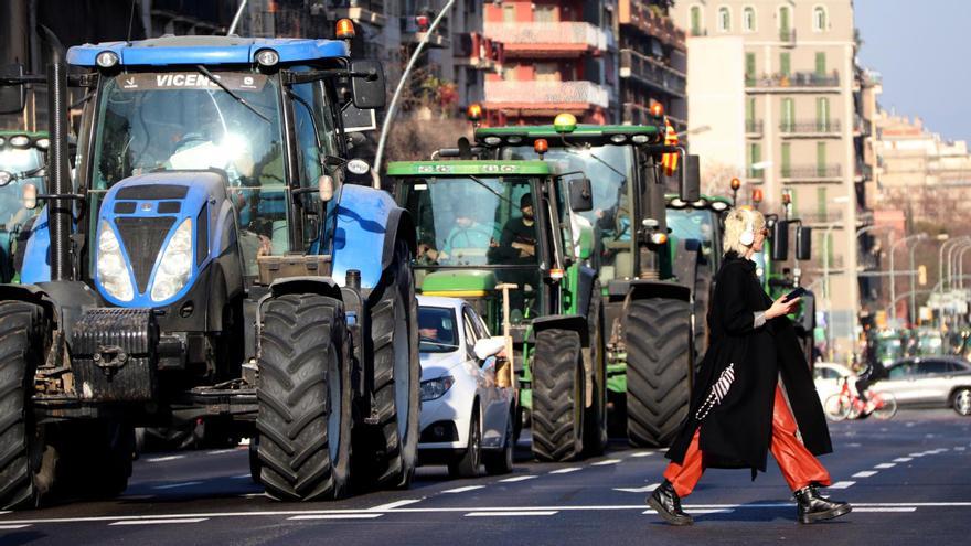 Una persona creuant l'Avinguda Diagonal amb tractors de fons