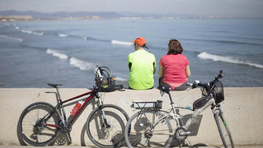 Una pareja observa el mar tras un paseo en bici.