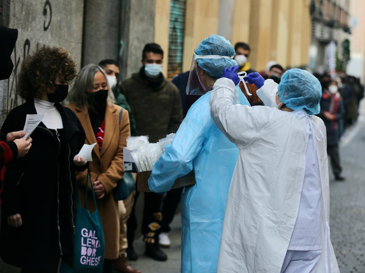 Una sanitaria pone el EPI a otra sanitaria para recoger test de covid de las personas que hacen cola, en una imagen de archivo.