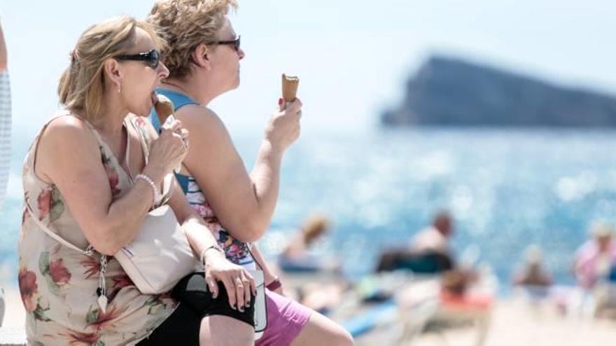 Una pareja de turistas mitiga los efectos del calor comiendo un helado en la playa de Levante de Benidorm.