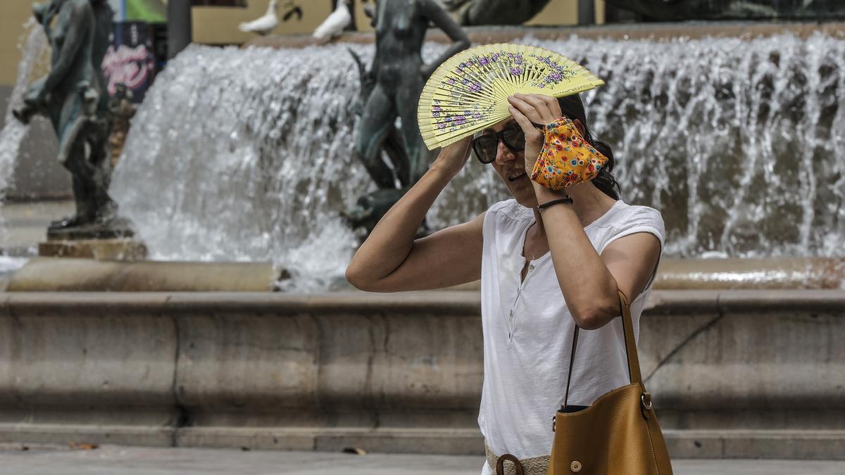 Una mujer se tapa la cabeza con un abanico para guarecerse de las altas temperaturas.