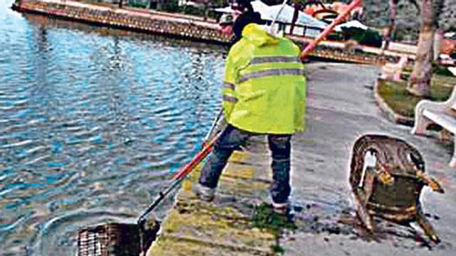 Un operario extrae residuos del lago Esperanza.