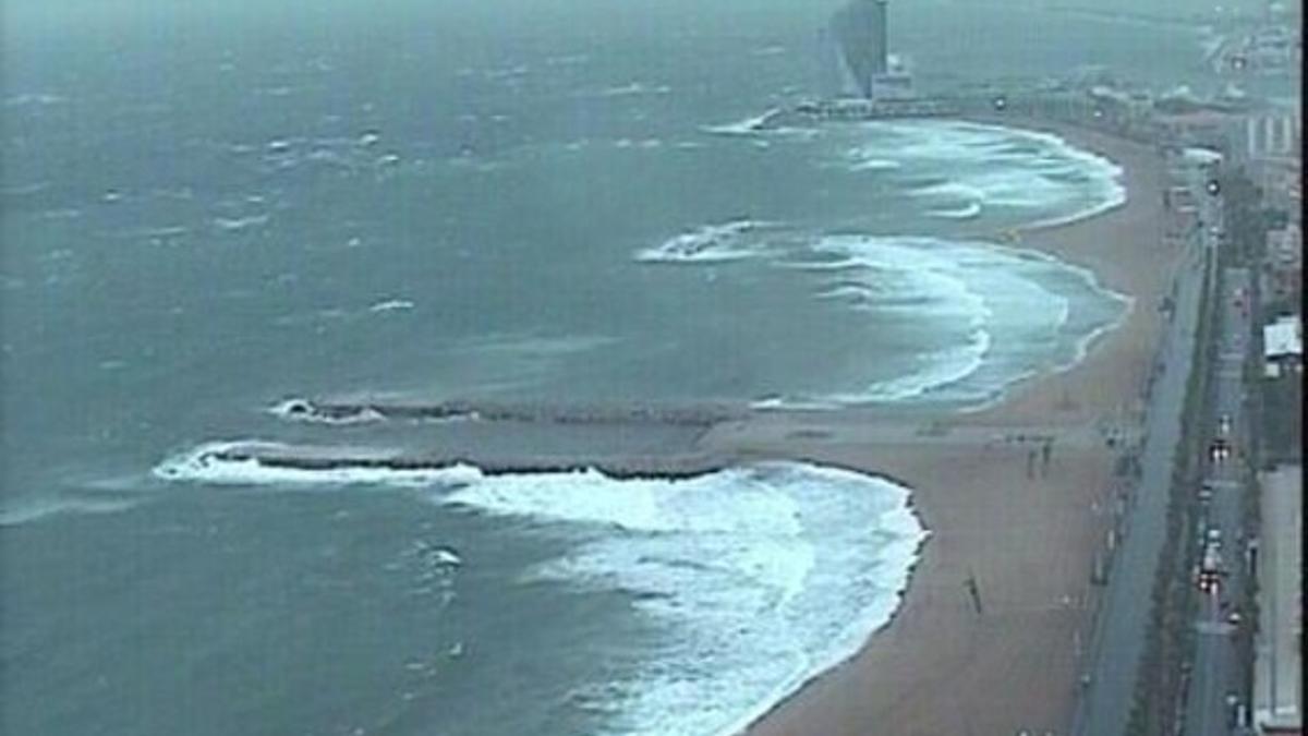 Vista de la playa de la Barceloneta, afectada por el temporal de viento y lluvia, con el Hotel W al fondo.