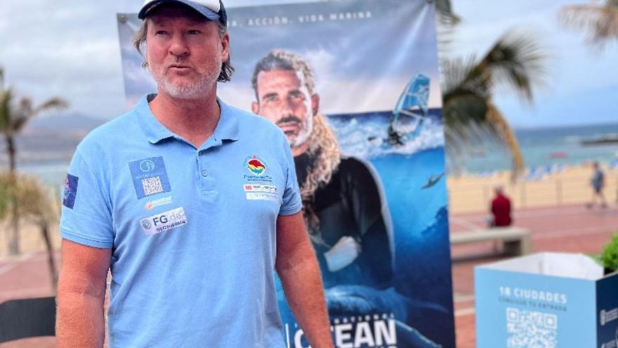 Björn Dunkerbeck posa junto al cartel promocional del International Ocean Film Tour.