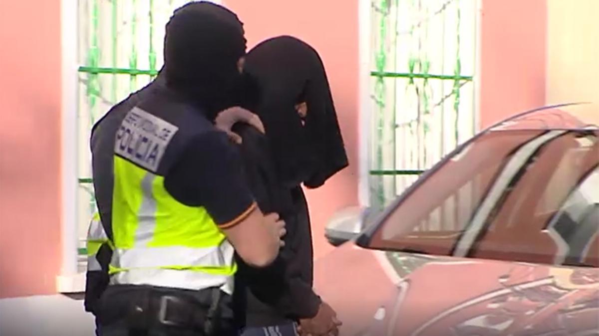 Trasllat del gihadista detingut a Madrid després del registre a la seva vivenda. El presumpte islamista ha sortit de casa seva amb el cap tapat.