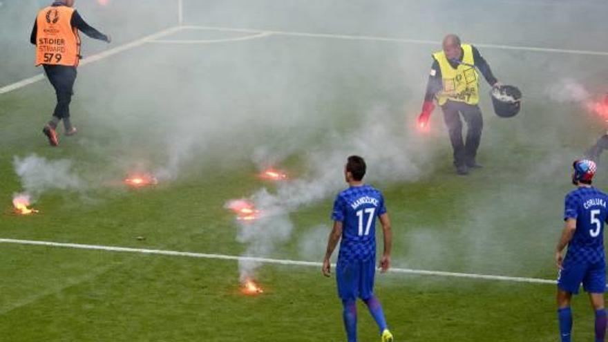 Personal del estadio recoge las bengalas que obligaron a interrumpir el partido.