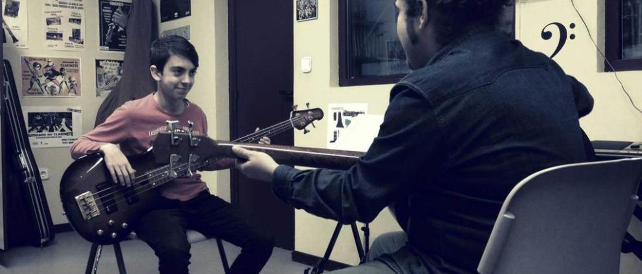 Jorge Arruñada recibe clases de bajo eléctrico de Alfonso Vega en un aula de la Escuela de Música de Llanera.