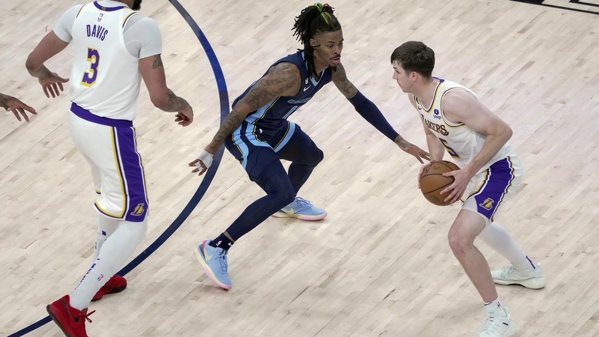 Austin Reaves bota la pelota bajo al vigilancia de Ja Morant, durante un Grizzlies - Lakers